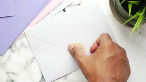 mano colocando una pegatina de agradecimiento en un sobre