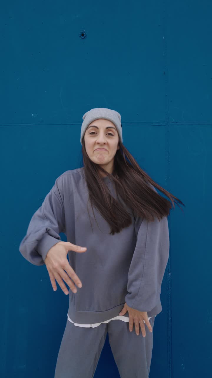 Woman in grey outfit in front of blue wall