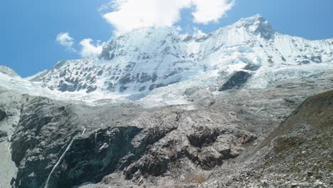 slow aerial approach reveals the brilliant turquoise laguna 69, then tilts up to showcase the majestic snow-capped cordillera blanca mountains in huascarán national park, peru