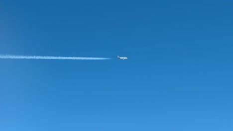 a twin-engine jet and its contrail crossing horizontally a blue sky. aerial footage taken from another jet cockpit flying bellow a parallel track