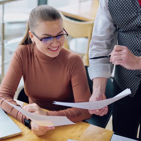 Young businesswoman and businessman working together in a light room with big windows. Beautiful woman laughs while discussing issues. Team work. Business video