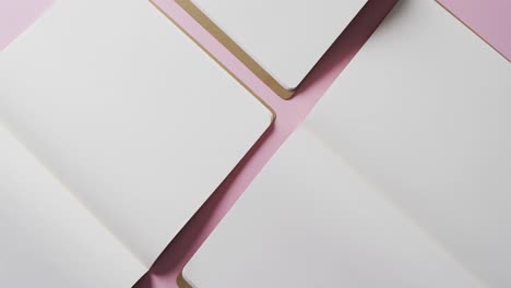 close up of open blank books with copy space on pink background in slow motion