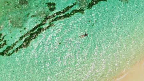 Un-Modelo-Flotando-En-Una-Impresionante-Playa-De-Aguas-Claras-En-La-Increíble-Isla-Caribeña-De-Petit-St-Vincent,-Granada