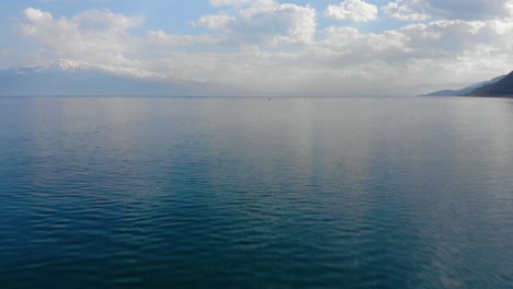Türkisfarbene-Wasseroberfläche,-Die-An-Einem-Frühlingstag-Schöne-Wolken-Reflektiert,-Fischerboote-Auf-Dem-See