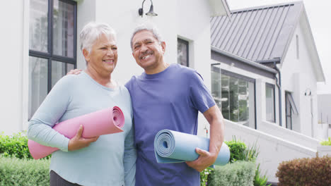 Retrato-De-Una-Feliz-Pareja-Diversa-De-Alto-Nivel-Con-Colchonetas-De-Yoga-En-El-Jardín