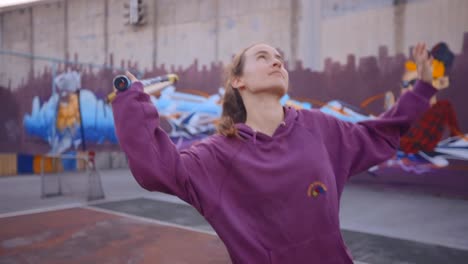 determined young woman learns tennis on urban court, with graffiti-filled backdrop