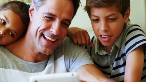 padre e hijos usando tableta digital en la sala de estar