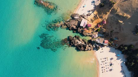 stunning aerial view of a pristine beach with crystal-clear turquoise water and charming beach huts.