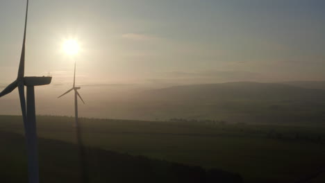 An-aerial-view-of-windfarm-turbines-slowly-turning-with-the-evening-sun-behind-them,-Aberdeensire,-Scotland