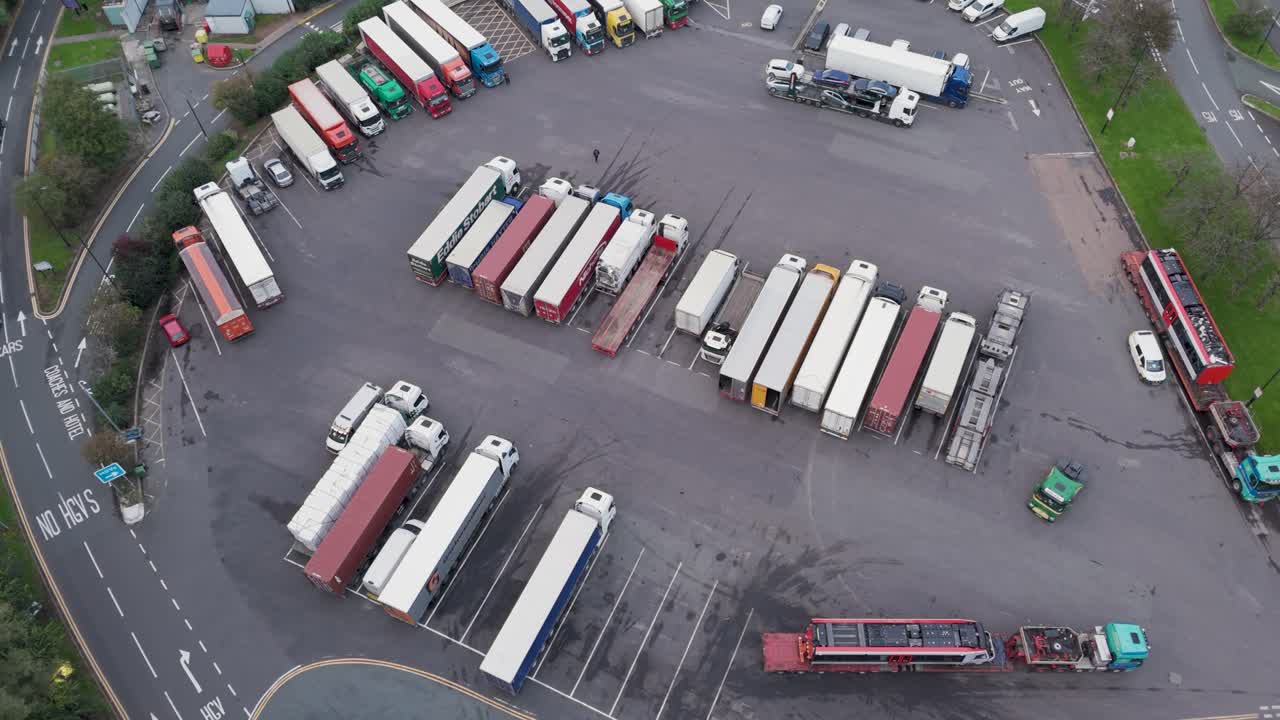 Rising drone aerial view of lorries and trucks parked at Gordano Motorway Services, illustrating rest stop activity, Bristol, UK, October 2024