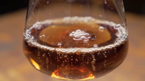 exploring the visual dynamics of carbonated beverage in a glass: a close-up journey from frothy bubbles to smooth surface transition