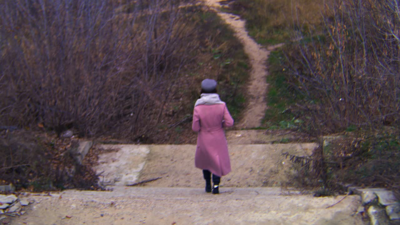 가을의 숲에서 계단을 고 있는 여자