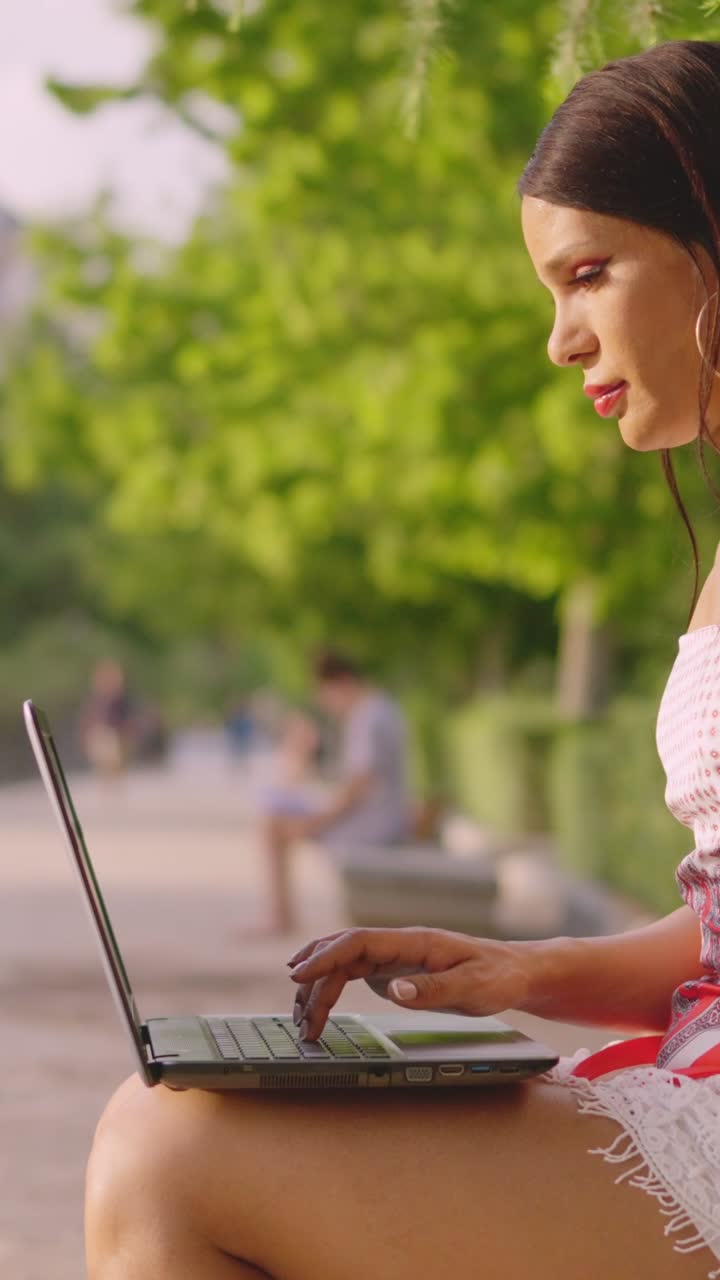 Woman working on laptop outdoors in a park