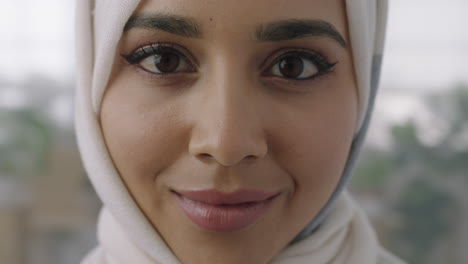 close up portrait of young muslim business woman looking up at camera confident wearing traditional hajib headscarf in office workspace background