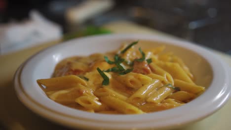 garnishing of cheesy penne pasta meal in white porcelain bowl