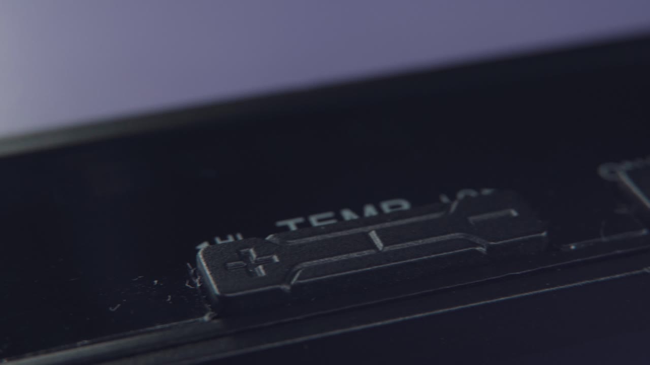 una foto macro detallada de una alisadora de cabello electrónica negra, un primer plano de la temperatura y los botones de encendido, equipos de peinado, iluminación profesional de estudio, video 4k