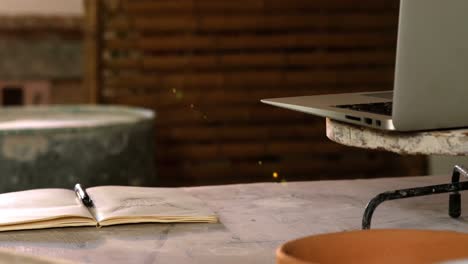 laptop, opened book, earthenware bowl on a worktop