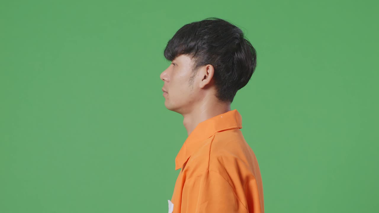 녹색 화면 배경에서 걸어다니는 수갑에 인 아시아 남성 죄수의 측면 뷰 클로즈업