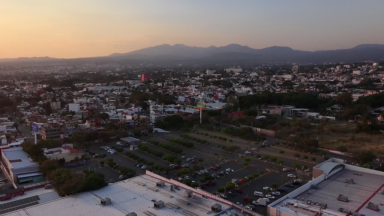 Vibrant aerial view of Cuernavaca city, showing a Walmart parking lot at sunset