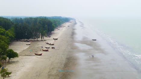 Luftaufnahme-Eines-Langen-Strandes-Mit-Traditionellen-Hölzernen-Fischerbooten-Und-Palmen