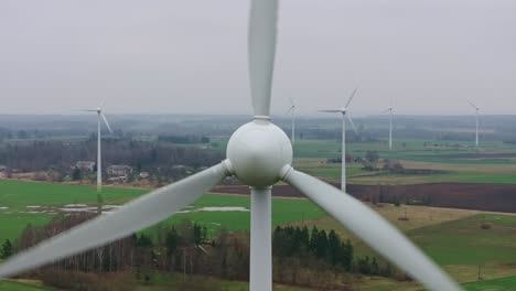 wind turbines blades spinning in strong winds over a green spring landscape, 4k