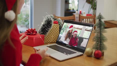 Happy-caucasian-woman-on-video-call-with-female-friend-and-daughter-at-christmas-time