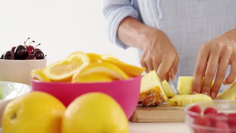 mujer cortando piña en la tabla de cortar
