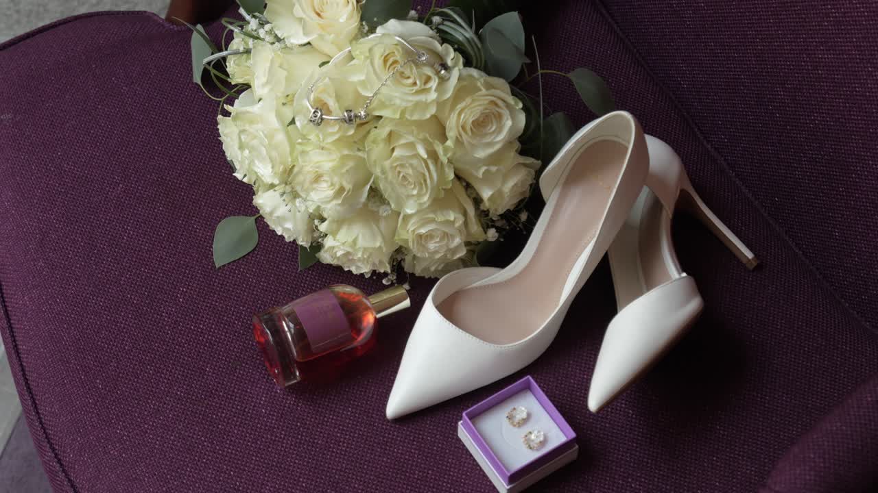 wedding bouquet shoes earrings and perfume arranged on chair
