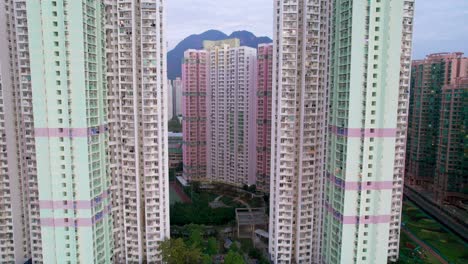 tall green and pink colored apartment towers with green artificial gardens in the densely populated ma on shan in hong kong's new terretories