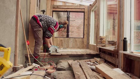 Man-Cutting-Excess-Wood-On-Flooring-Of-Greenhouse