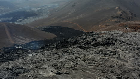 Fly-over-large-hole-in-cooling-lava-layer-emitting-smoke.-Volcanic-landscape-after-volcano-eruption.-Fagradalsfjall-volcano.-Iceland,-2021