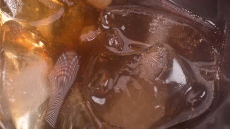 static-shot-of-cola-and-ice-with-little-bubbles-coming-up,-4k-macro-drink