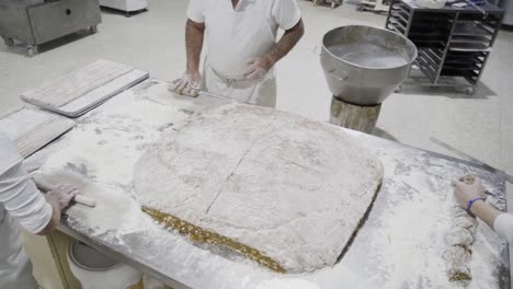 slow motion handheld shot from above of confectioners from a candy factory preparing a dough on a countertop into delicious pastries