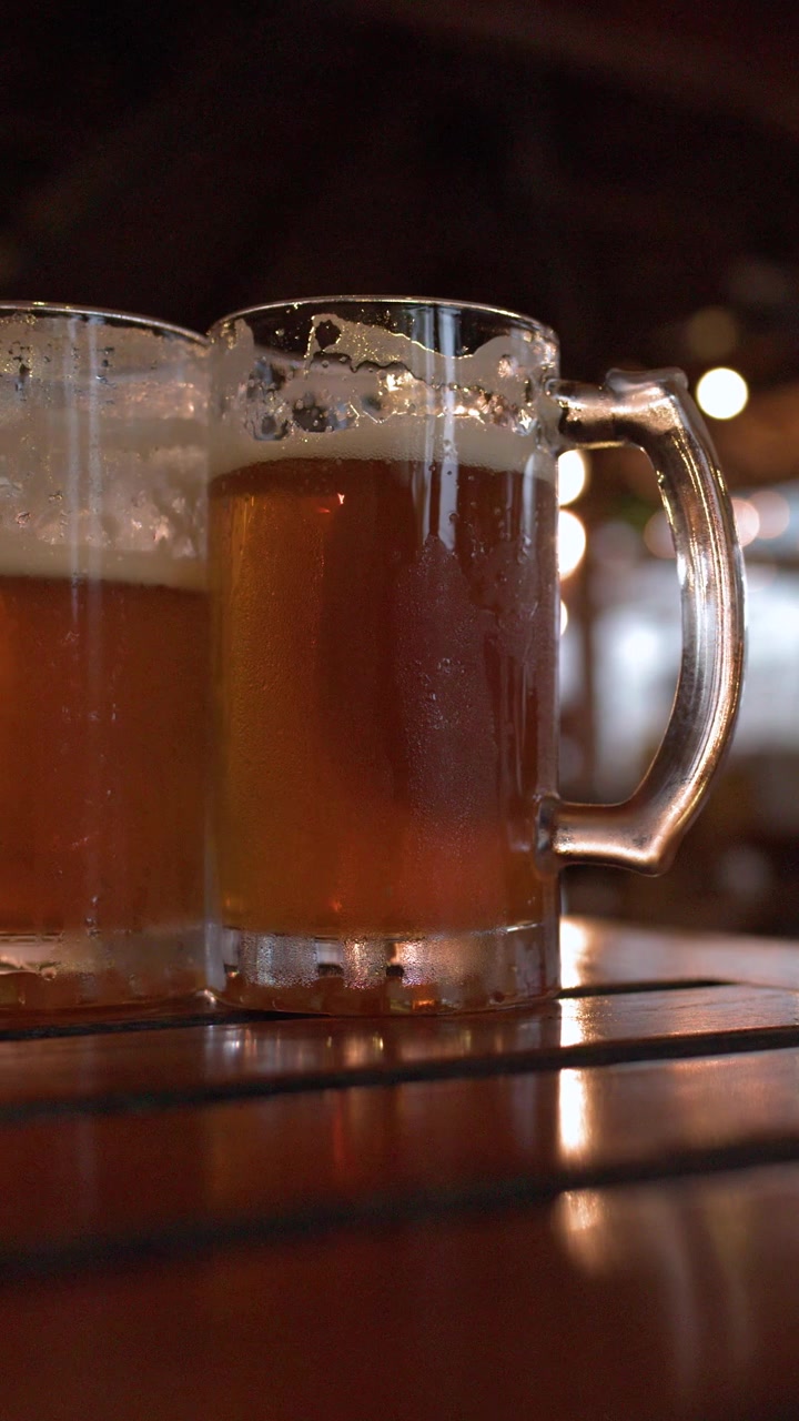 Due boccali di birra freddi su un tavolo di legno in un bar