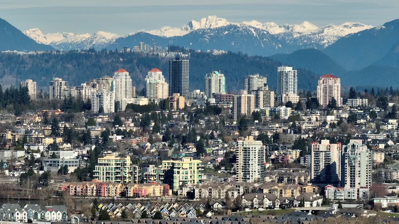 Skyline urbano compatto contro montagne innevate a New Westminster, Columbia Britannica, Canada. Ripresa aerea.