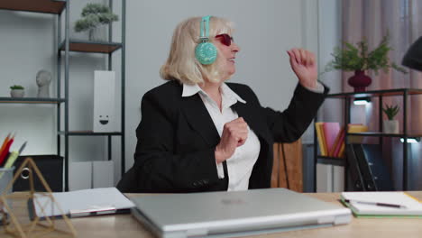 feliz mujer de negocios senior bailando baile de victoria celebrando fin de semana vacaciones éxito ganar en la oficina
