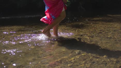 slow motion of a woman's feet walking in a shallow river