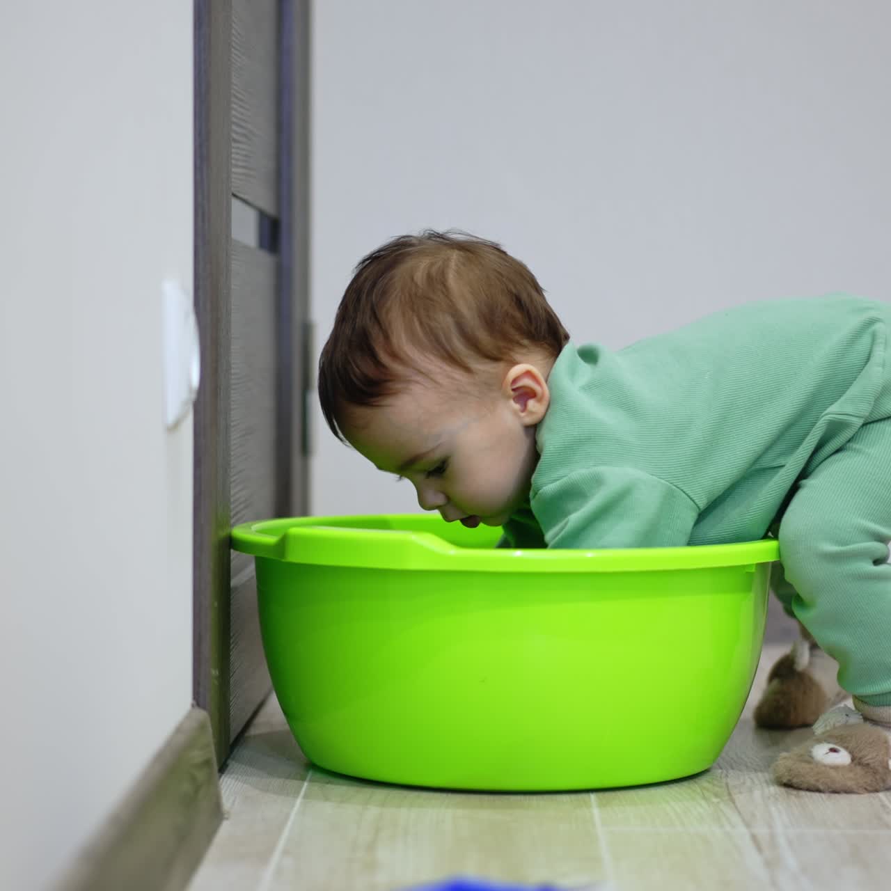 Little sweet toddler put his hands inside the washbowl. Baby tries to get into the tub
