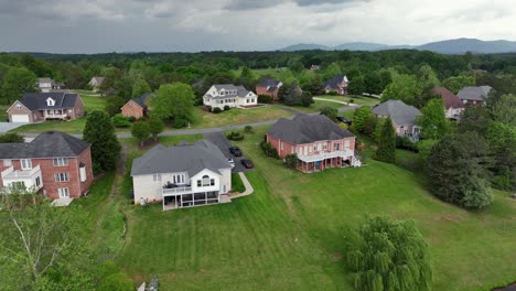 single family houses with balcony veranda and hillside garden in american suburb. aerial approaching shot. cloudy day in spring. private access to river. wide shot.