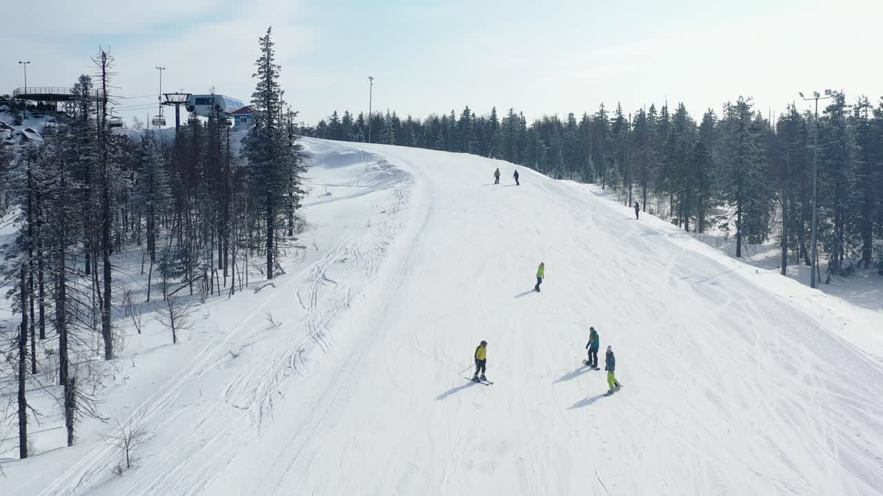 vista aérea de esquiadores y snowboarders en una ladera nevada de la montaña