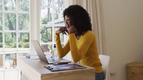 Afroamerikanische-Frau,-Die-Einen-Videochat-Auf-Dem-Laptop-Führt,-Während-Sie-Zu-Hause-Auf-Ihrem-Schreibtisch-Sitzt