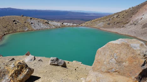 Pan-across-stark-volcanic-dome-lake-high-above-plateau-landscape