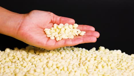 hand releasing white chocolate chips onto pile