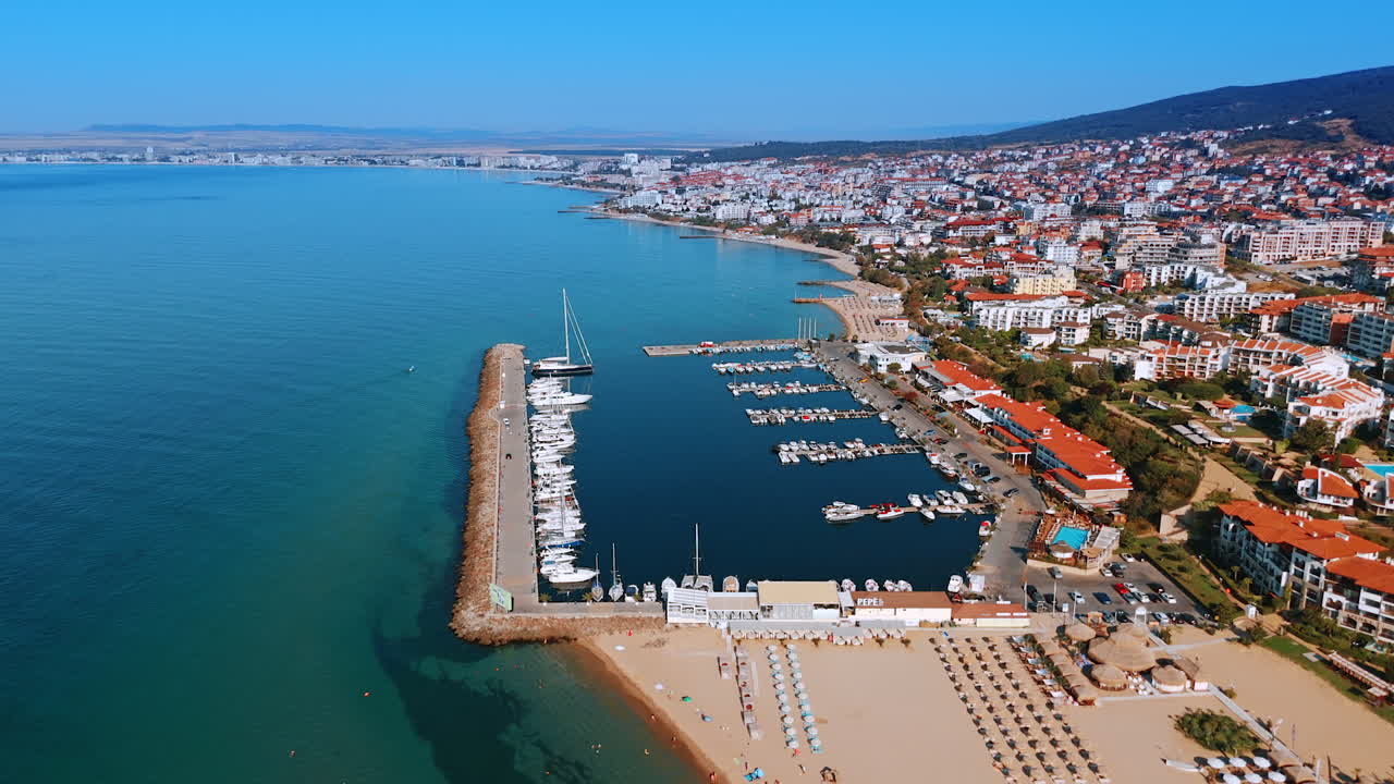 Coastal view with marina beach. A stunning aerial view of a marina filled with boats, nestled along a vibrant coastal town under a clear blue sky