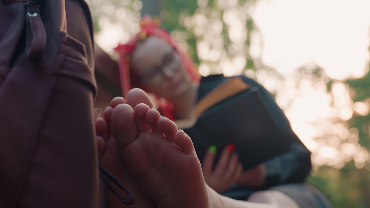 햇빛 아래 맨발로 밖에서 책을 읽는 학생, 햇빛 아래에서 공부하면서 맨발로 편안하게 야외에서 휴식을 취하는 캐주얼한 학생, 햇살을 쬐며 맨발로 공원에서 여유롭게 공부하는 학생