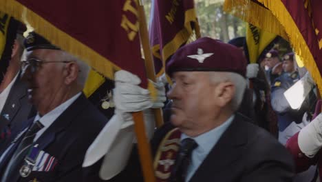 veterans, proudly carrying maroon military flags, march in unison during a military commemoration. the image captures the solemnity and honor of the occasion as they pay tribute to their service
