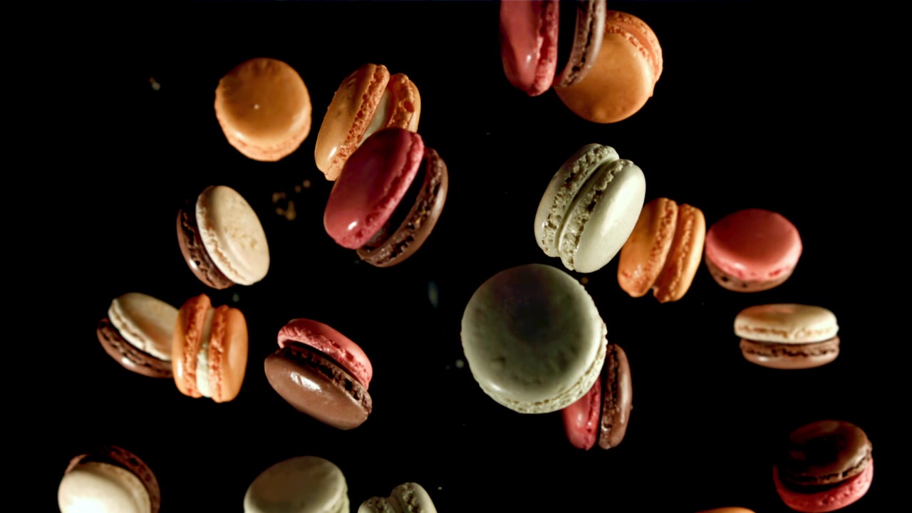 Colorful Macarons Flying Upwards in Slow Motion on Black Background