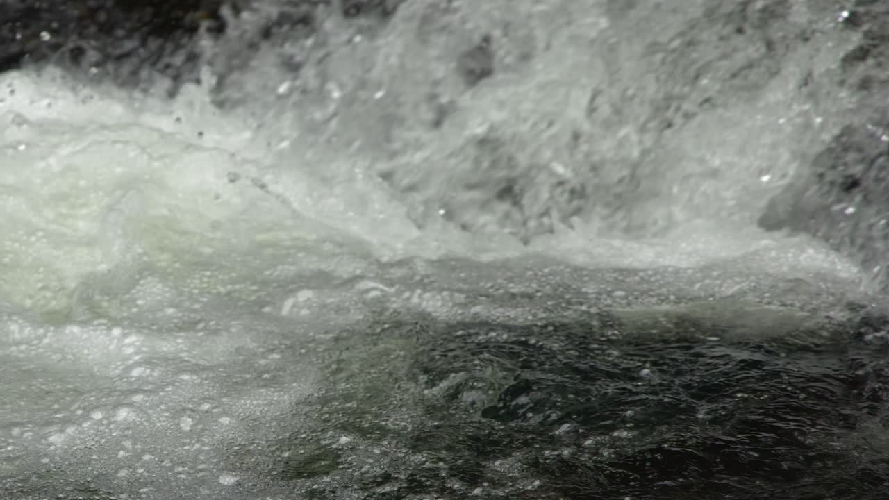 Un'inquadratura statica ravvicinata cattura l'acqua bianca turbolenta che scorre rapidamente sulle rocce a Palau.