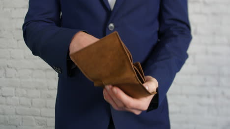 a business man looking for coins in an empty wallet