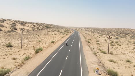Aerial drone shot of a rider passing through desert villages and dry fields on a long ride.